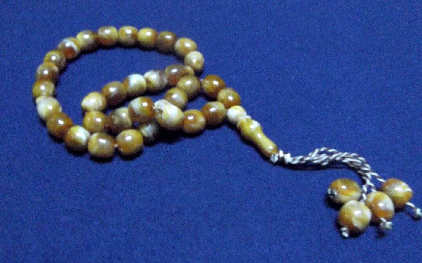 Amber tasbih prayer beads on a blue cloth